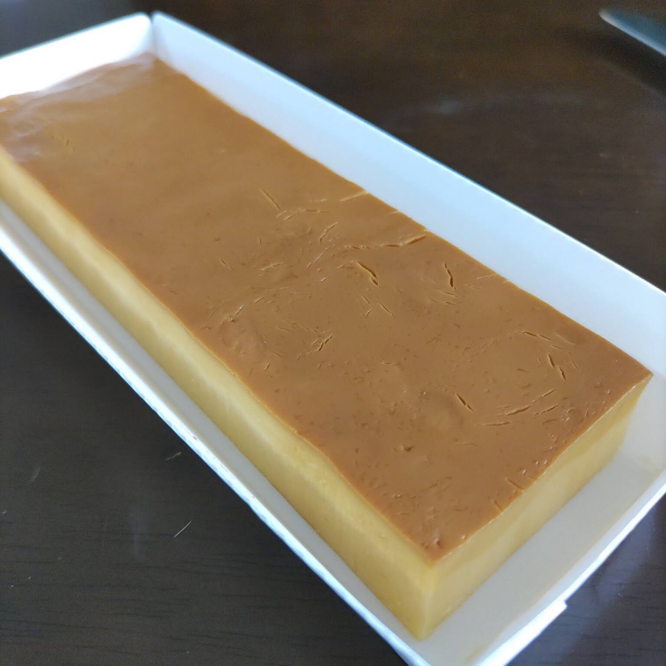 三和の純鶏名古屋コーチンたまごぷりんの写真。外観は、厚みのある帯のようでとてもプリンとは思えない。プリンに対する固定観念を打ち砕く独特な形をしている。