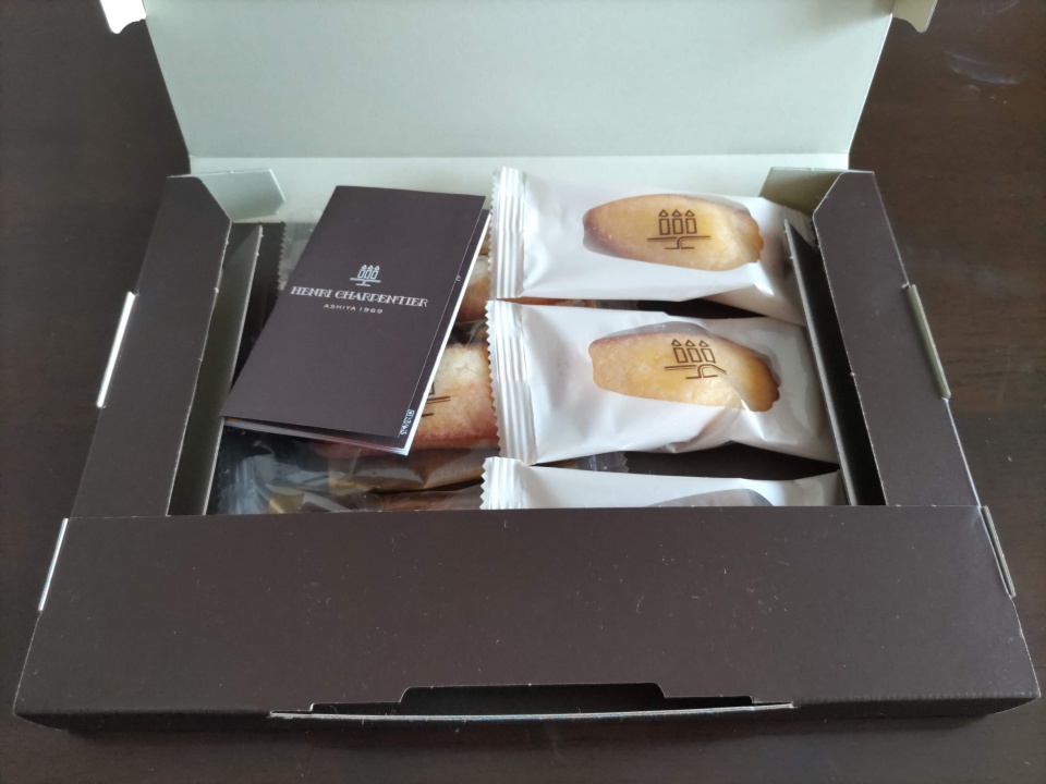 アンリ・シャルパンティエのフィナンシェとマドレーヌ詰め合わせの化粧箱のふたを開けて撮影した写真。個包装された焼き菓子が整然と並んでいる。