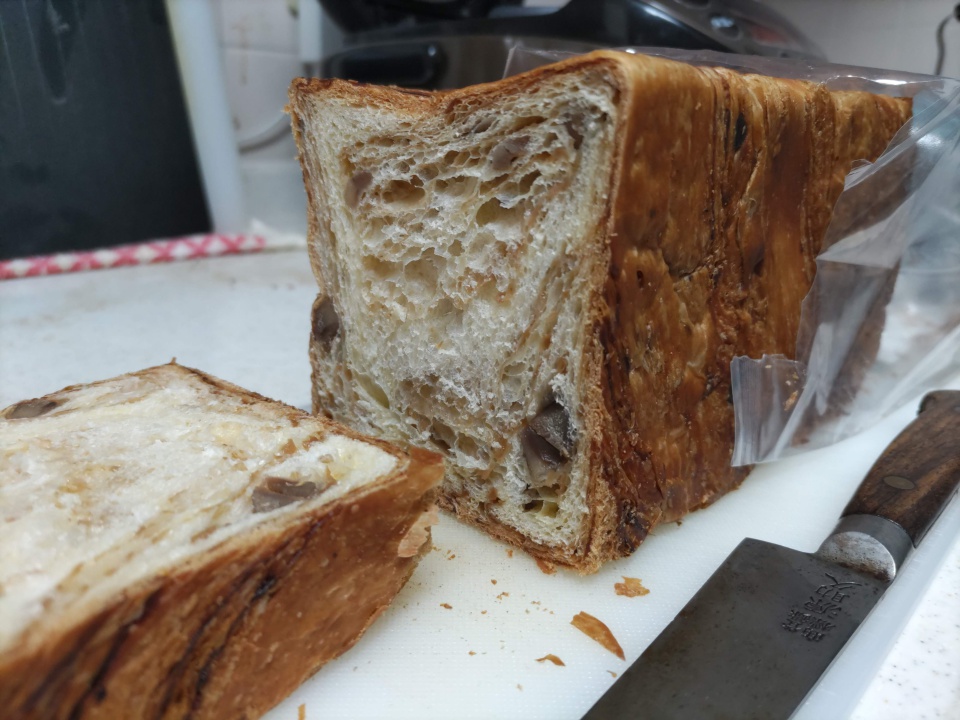 高級スイーツデニッシュ栗1斤を包丁で切った直後の写真。まな板の上に置かれたデニッシュの断面から、層状の生地と中に入った栗がはっきりと見え、焼き色のついた外側とふんわりした内側の対比が分かる。