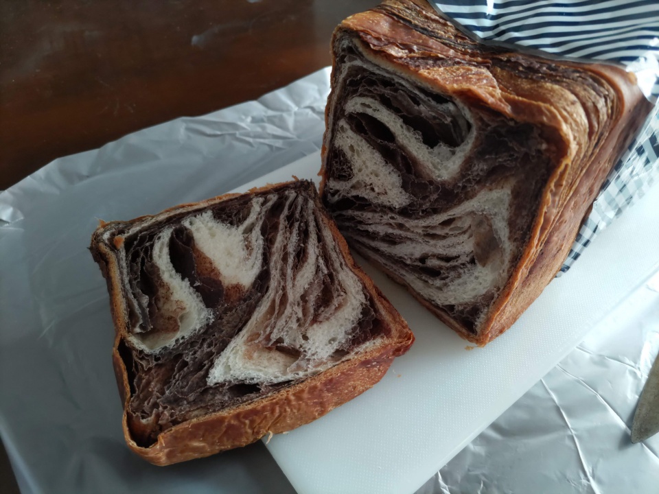 アンデ「ショコラーデデニッシュ」1斤を包丁でカットした直後の断面を写した写真で、チョコレート生地とプレーン生地が層状に折り重なり、マーブル模様がはっきり見える様子が分かる。