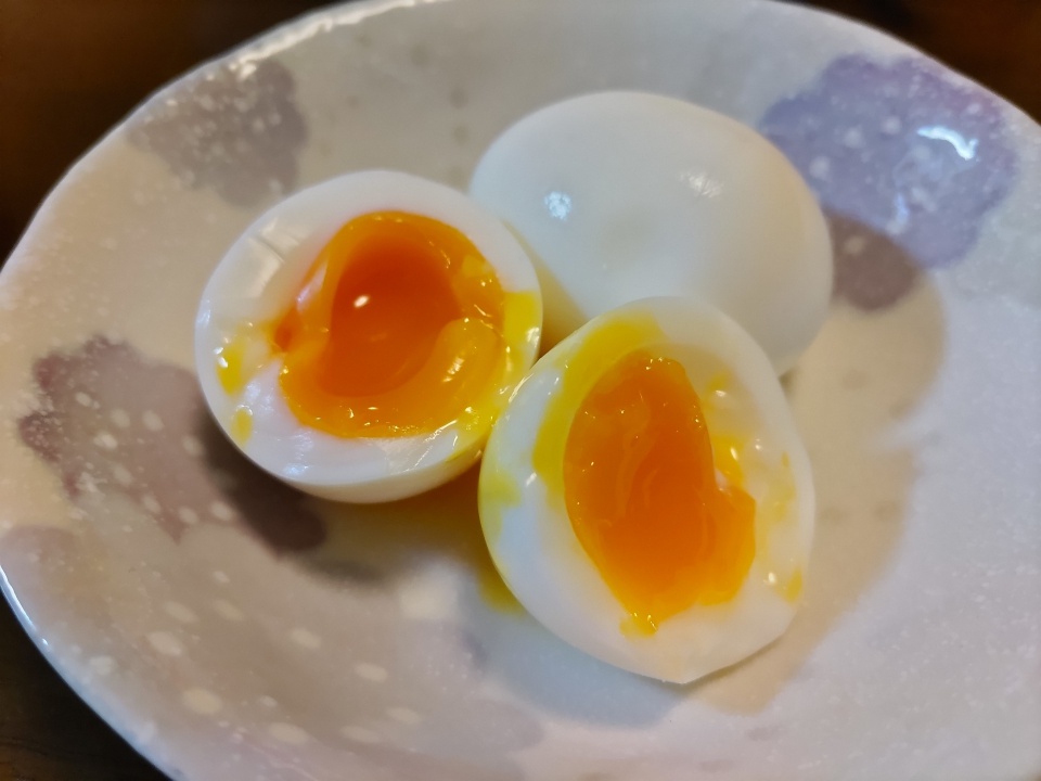 半分に切った半熟ゆで卵が器に盛られ、オレンジ色の卵黄がとろりと流れ出ている様子