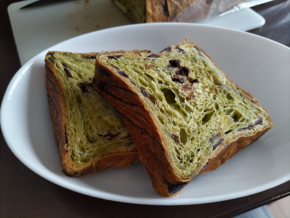 メイズテーブルのスイーツデニッシュ「Wチョコ抹茶」を2切れ皿に盛り付けた写真。抹茶色の生地の中にチョコレートが練り込まれた断面が見えるデニッシュパン。