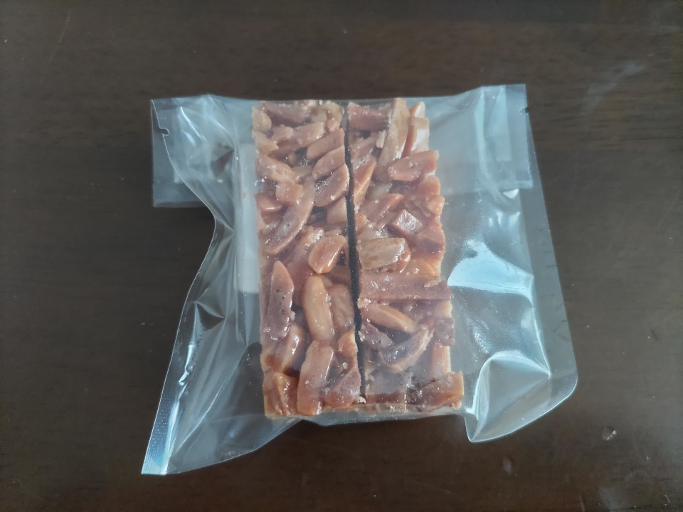 ケーキハウスカネヤマのアマンディーヌを1パック取り出した写真。透明の個包装袋に入ったアーモンドたっぷりの焼き菓子。