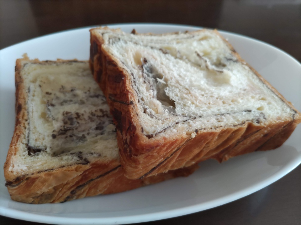 桜餡が練り込まれたデニッシュを白い皿に2切れ盛り付けた写真。断面からこし餡の層とバターの層が見え、外側はこんがりと焼き色がついている。