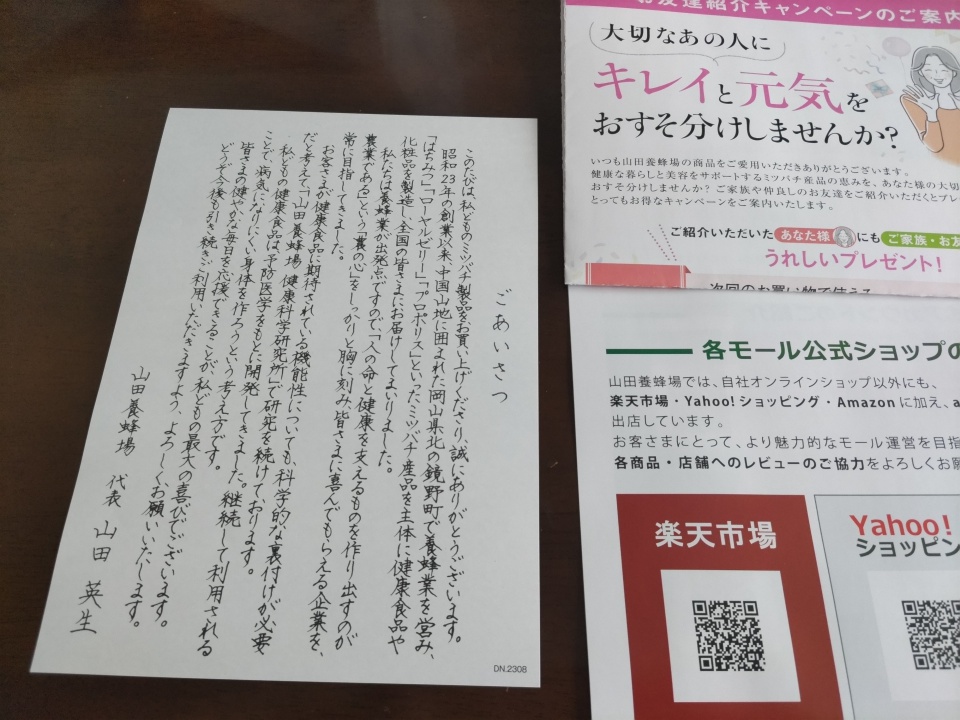 山田養蜂場の社長あいさつが記載された手紙と、キャンペーンや公式ショップ案内のチラシを並べて撮影した写真。QRコード付きの案内や紹介キャンペーンの情報が掲載されている。
