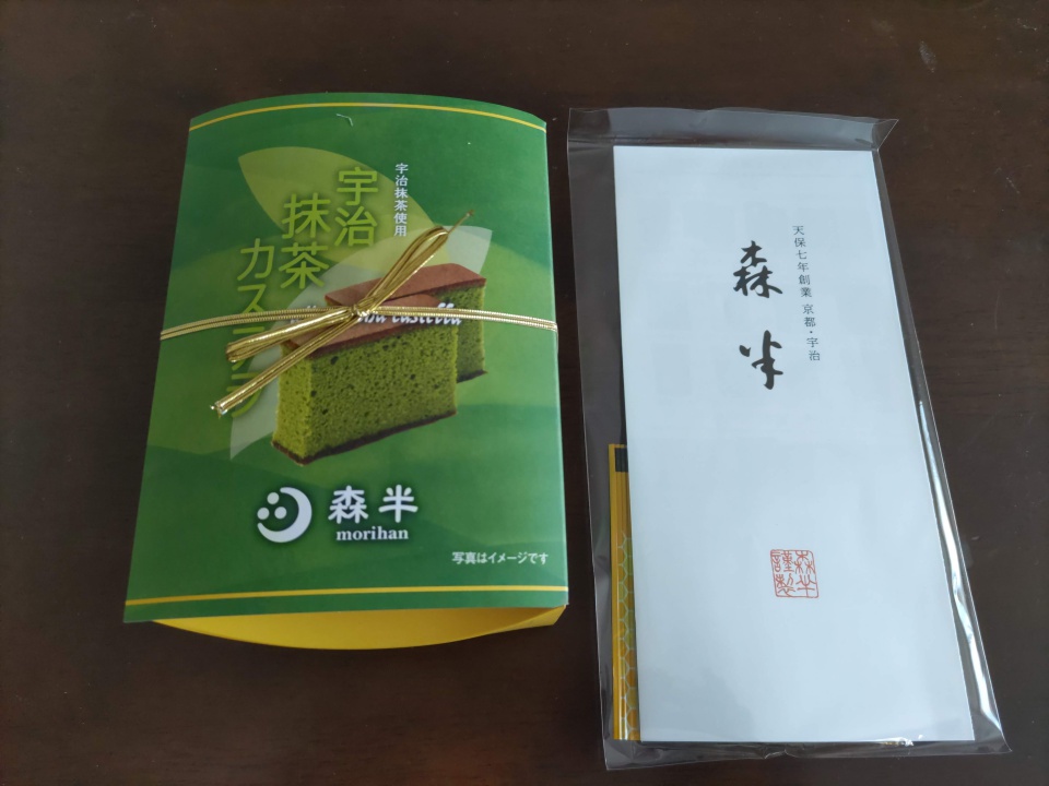 森半の極上手作り宇治抹茶カステラの箱を外箱から取り出した様子。緑色の包装と金色のリボンで丁寧に包まれている。