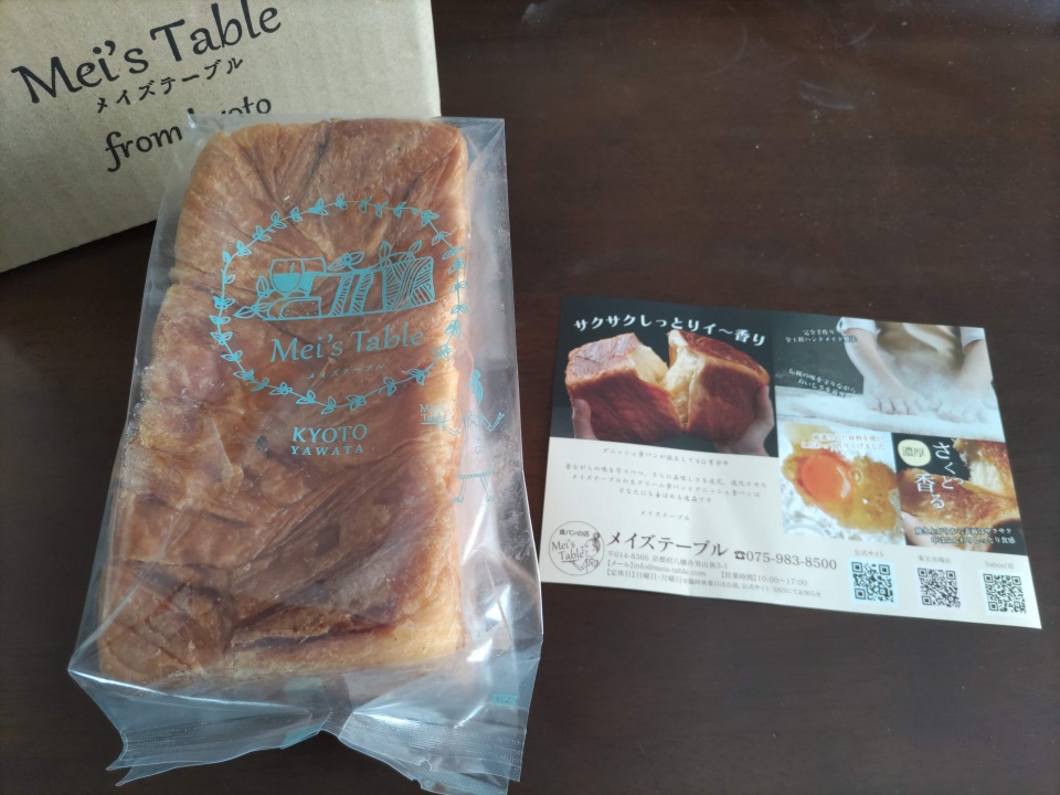 透明な袋に入った瀬戸内レモンデニッシュと、商品紹介のチラシがテーブルの上に並べられている。袋には「Mei’s Table KYOTO YAWATA」とロゴが印字され、奥には同ブランドのダンボール箱が見える。