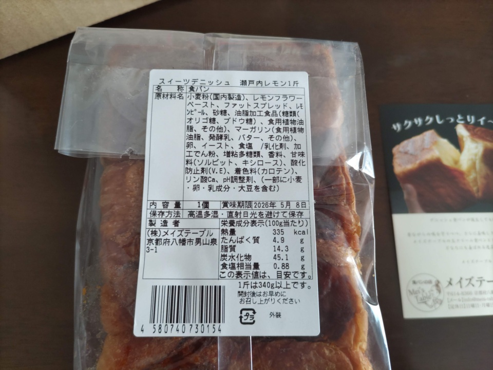 透明な袋に入った瀬戸内レモンデニッシュの裏面ラベルのクローズアップ。商品名、原材料、賞味期限、栄養成分表示などの情報が白いシールに記載されている。