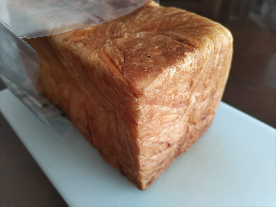 袋から取り出した瀬戸内レモンデニッシュを白いまな板の上に置いた様子。こんがりと焼き色のついた表面と、層になった生地の質感がはっきりと見える。