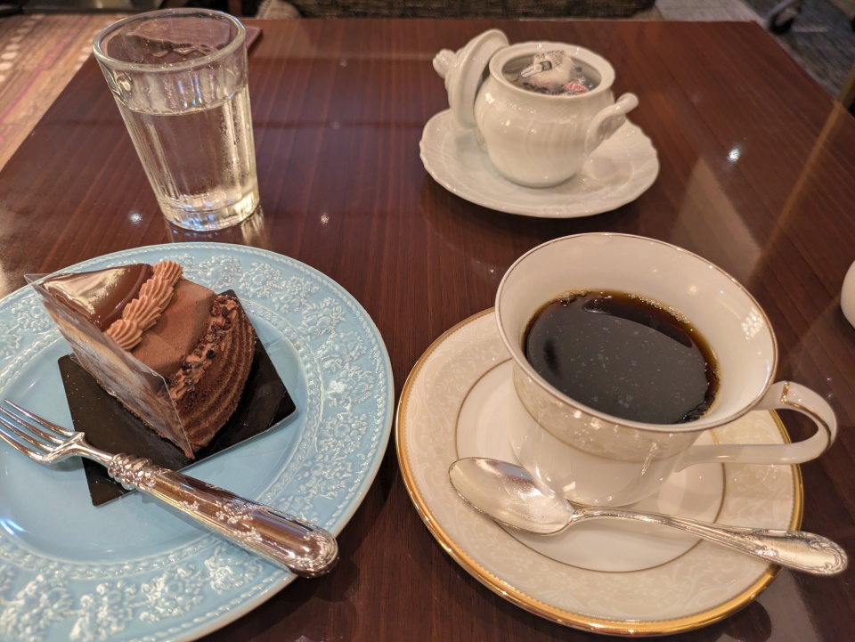 ホテルグランヴィア大阪ティーラウンジのケーキセット「STORY～重なる想い～」。水色の皿に盛られた層状のチョコレートケーキと、白いカップに入ったコーヒー。